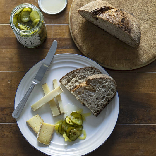 Plated bread, cheese, and pickles on a wooden table
