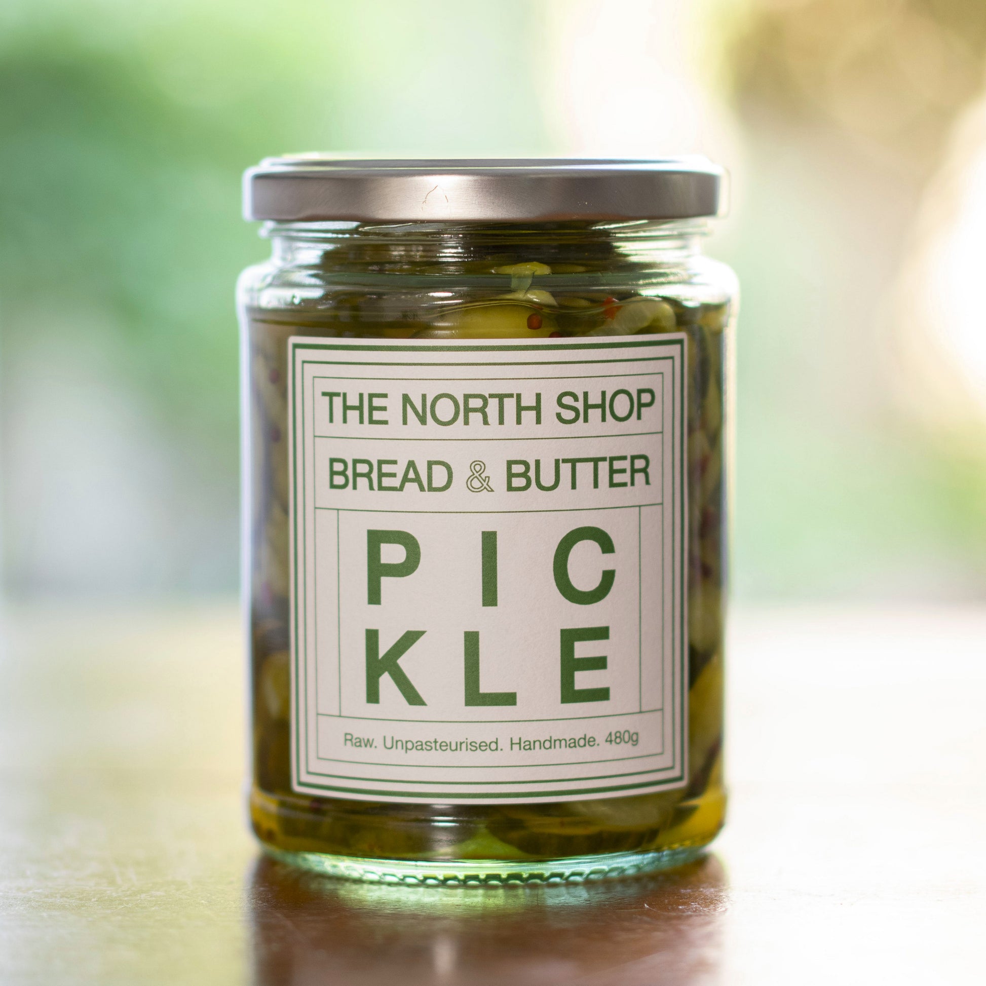 A glass jar of pickles on a wooden table.