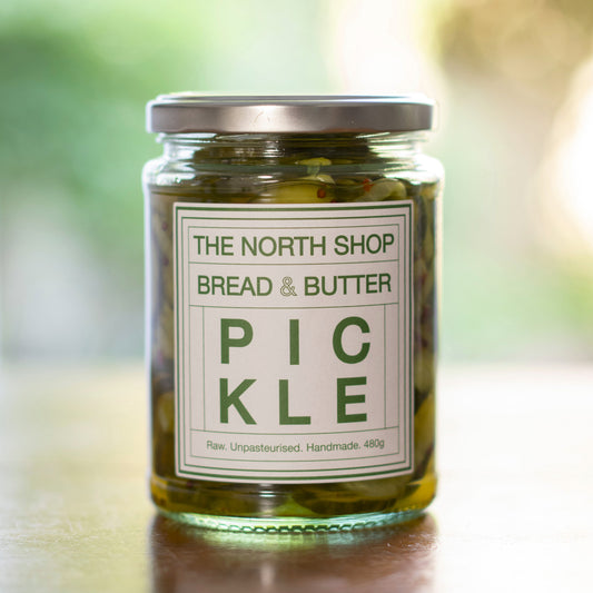 A glass jar of pickles on a wooden table.