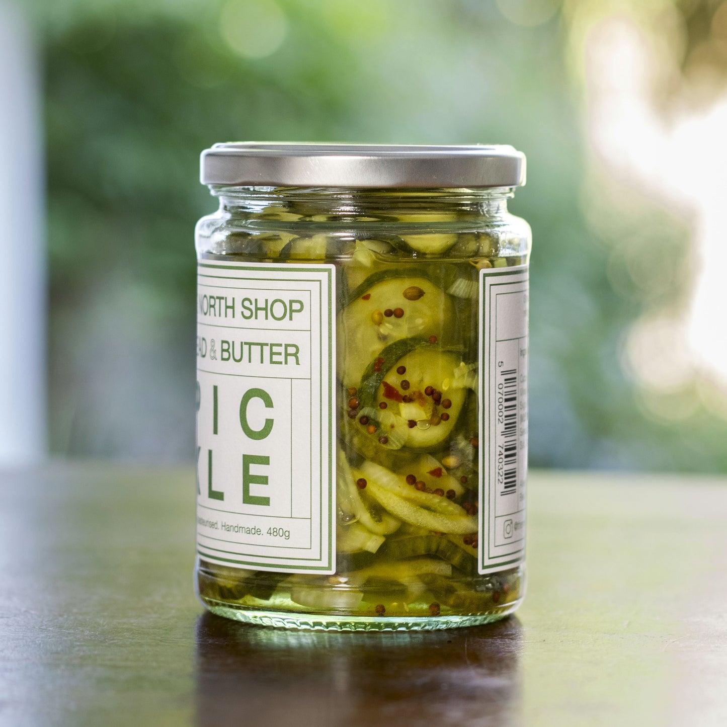 Jar of pickled vegetables on a wooden table with a blurred green background