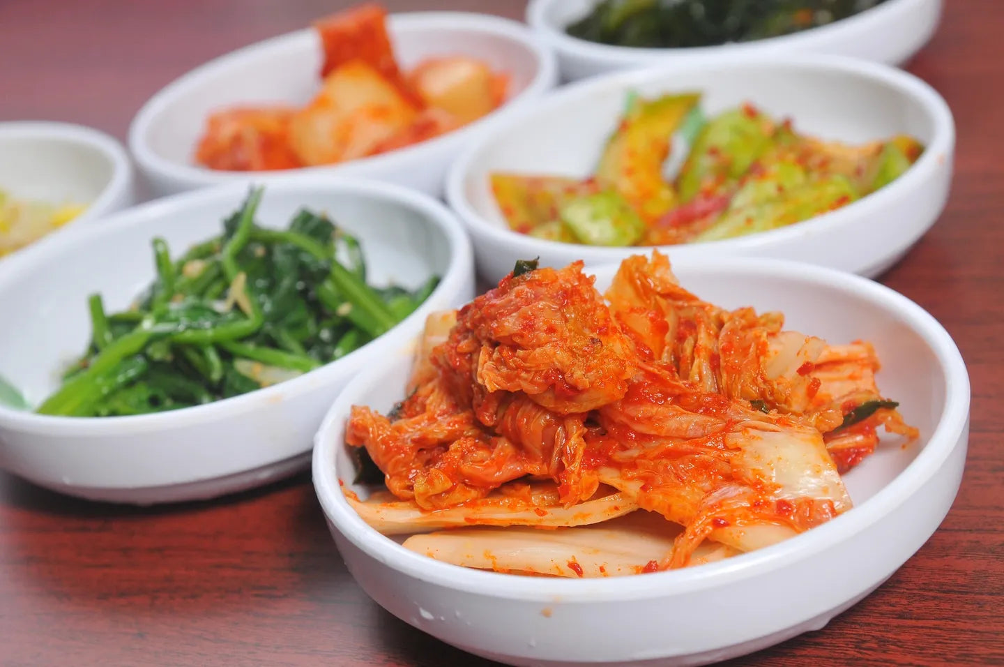 Several white ceramic bowls containing various fermented Asian foods.