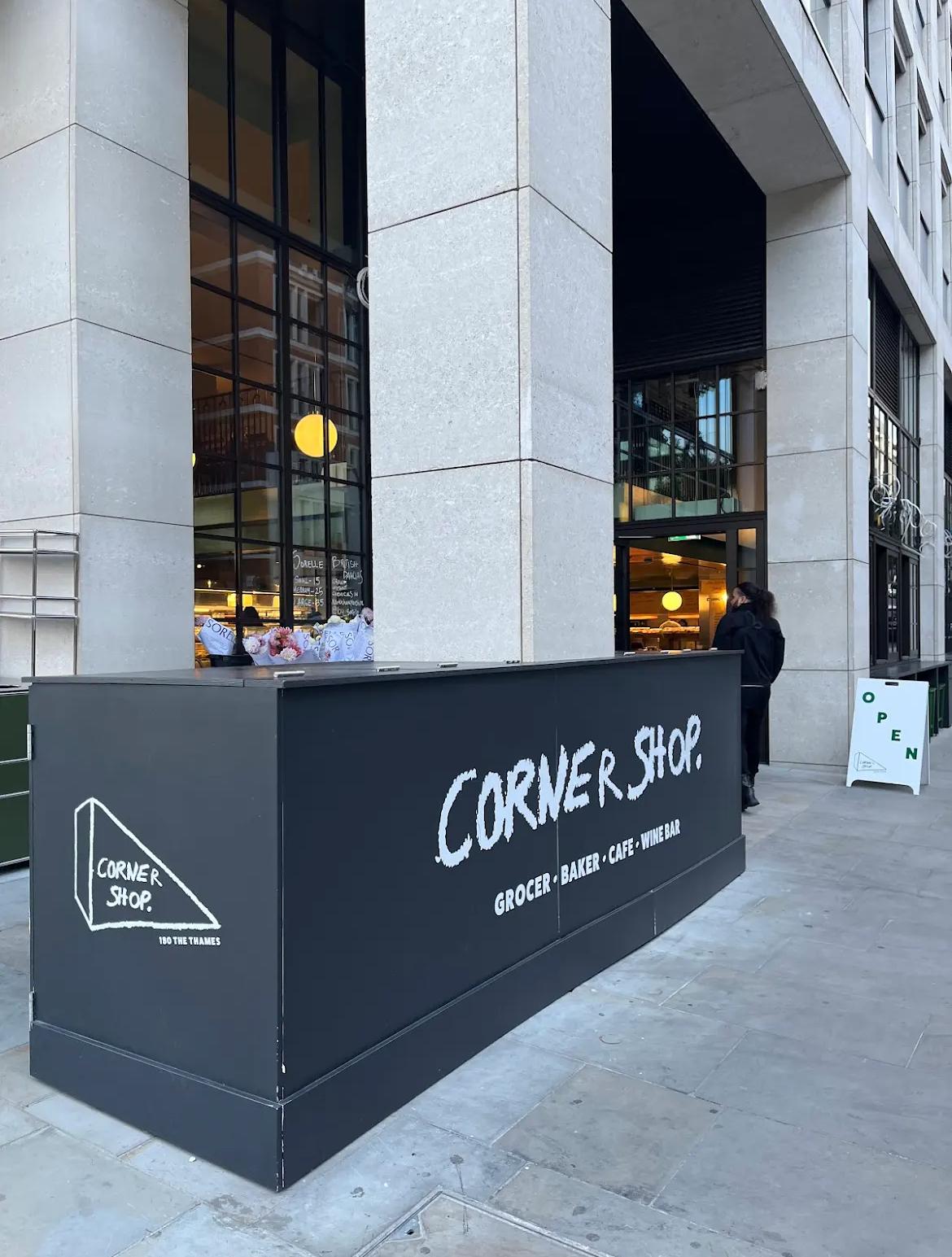 Black counter with 'Corner Shop' branding in front of a building