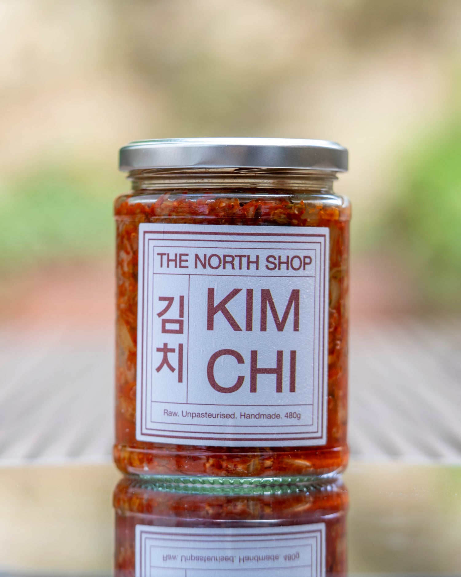 A jar of The North Shop kimchi on a glass mirror.