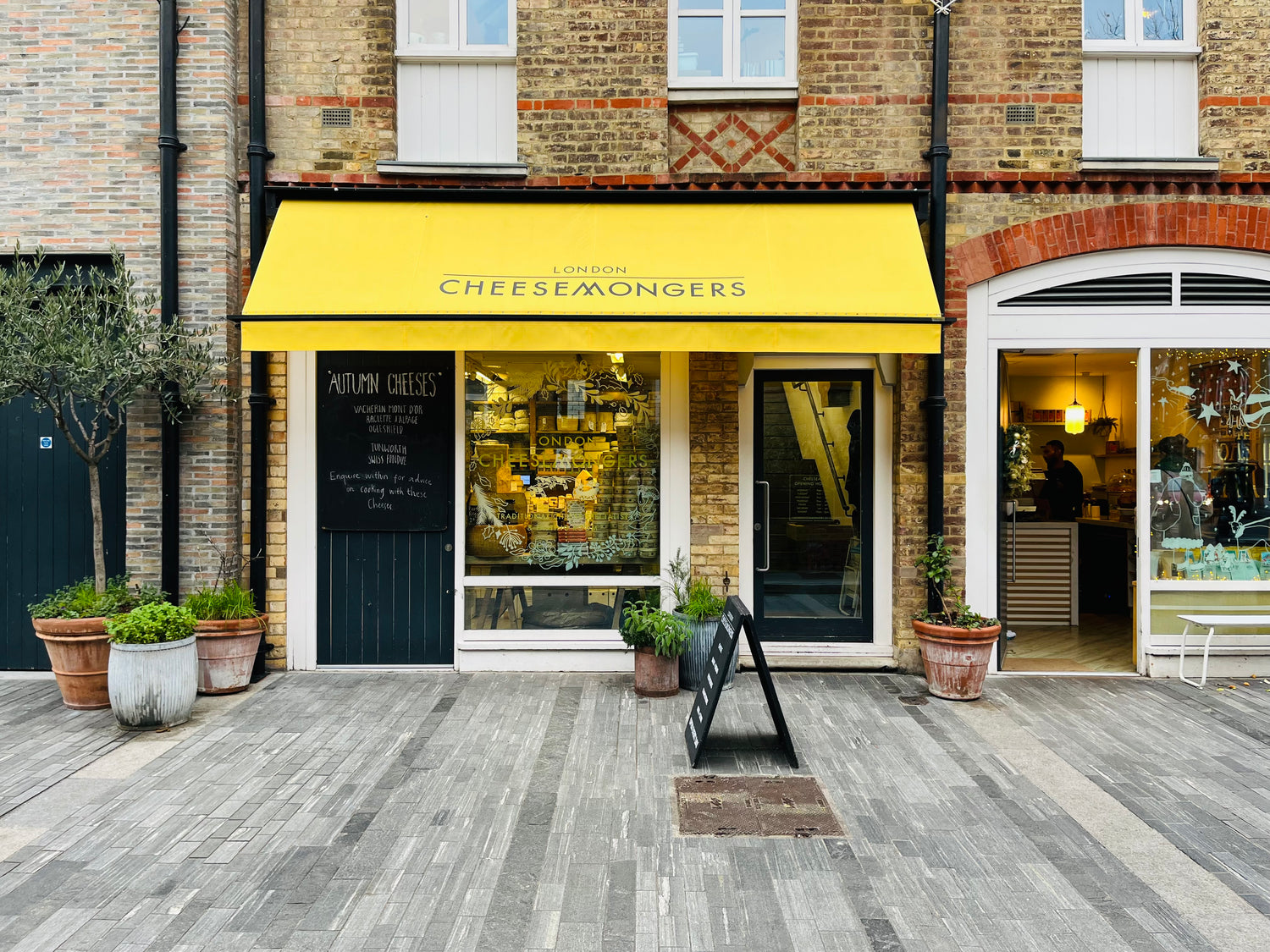 A shopfront with a bright yellow awning on a paved street.