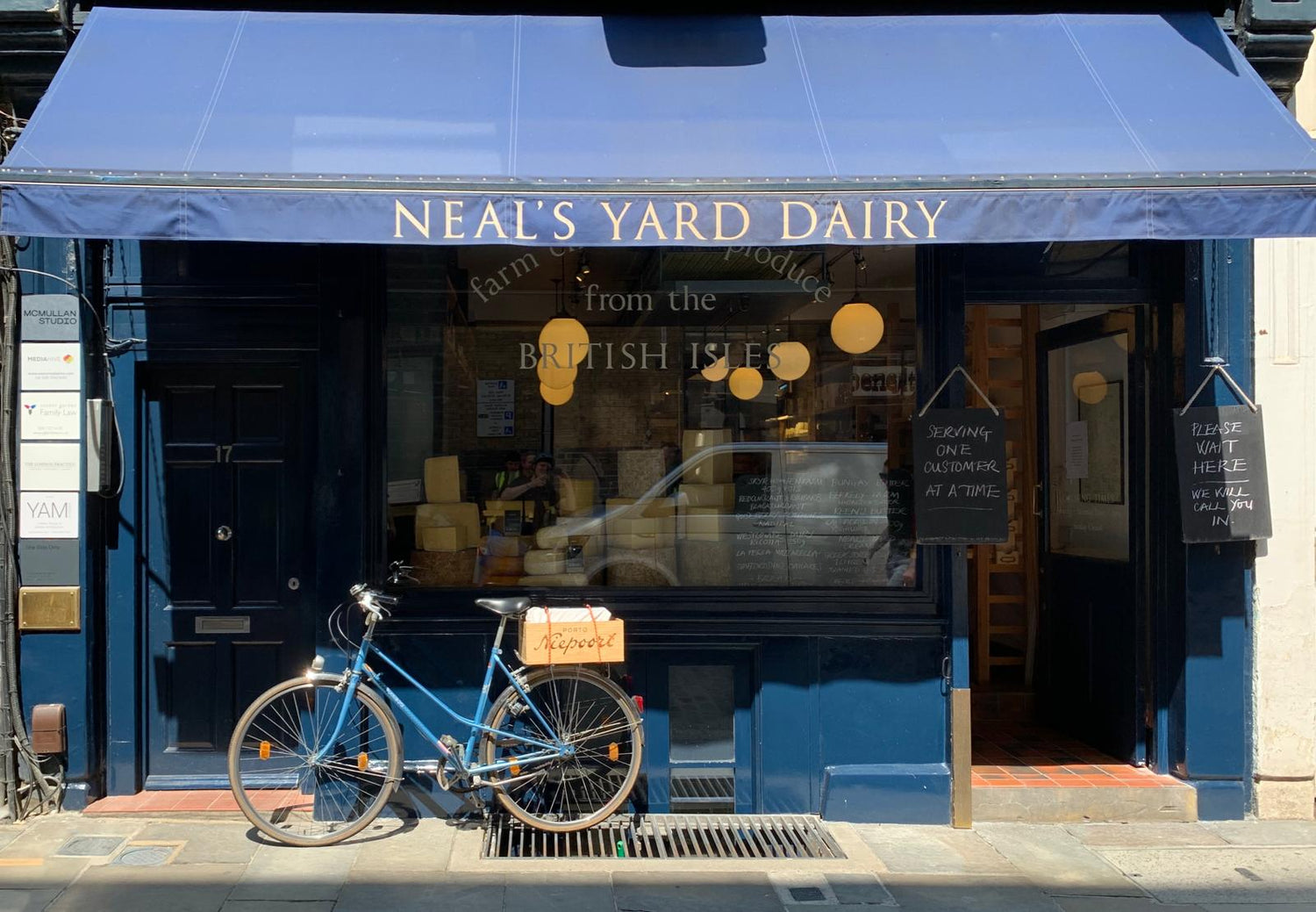 A blue bicycle in front of a Neal's Yard Dairy shop.