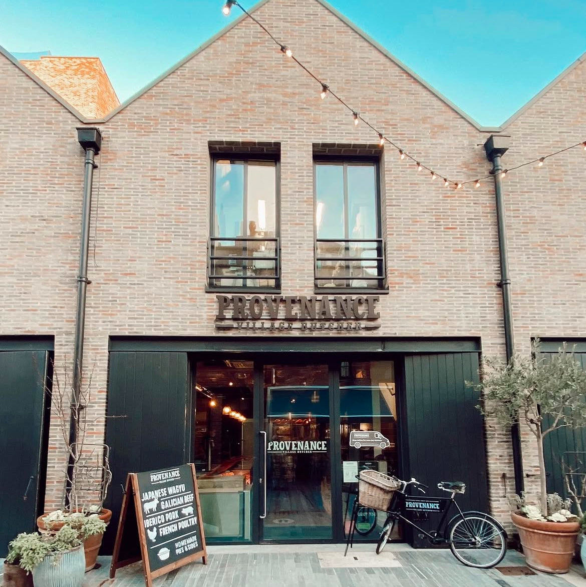A brick and glass fronted shop on a street.