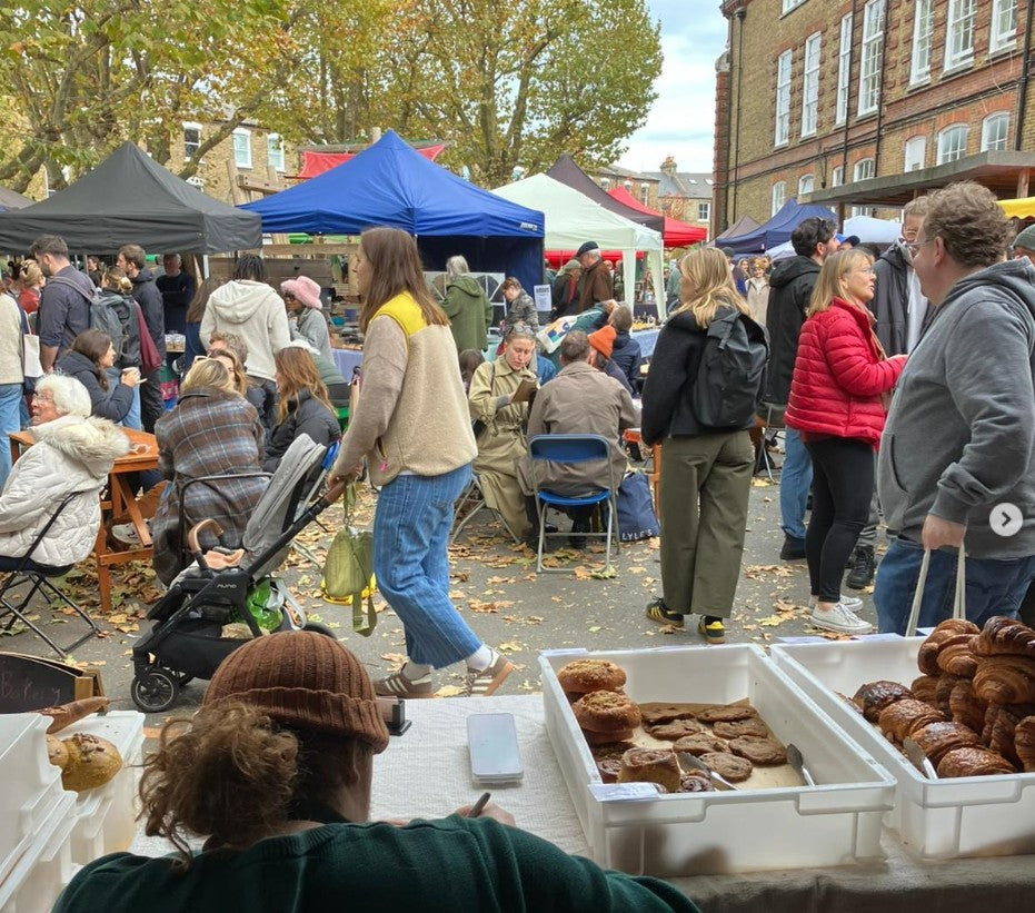 Outdoor market scene with people and food stalls.